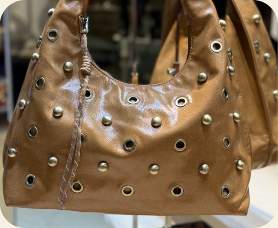 Bolsa hobo com ilhoses e tachas